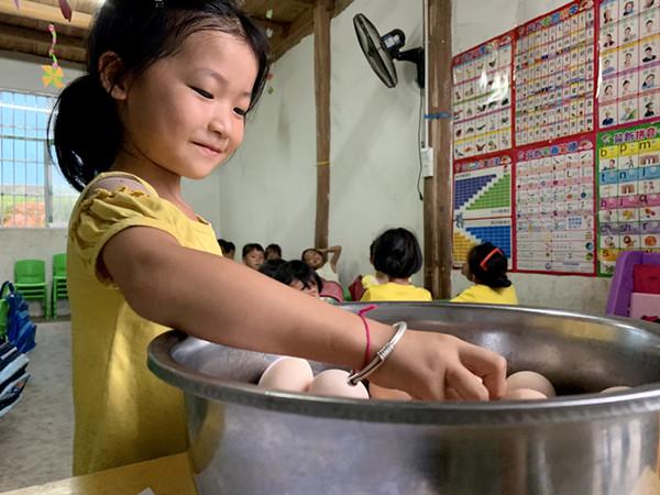 图说:小智同学正在帮老师发放鸡蛋。