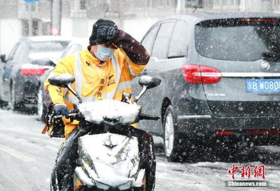 资料图:2月14日,外卖小哥在雪中送餐。