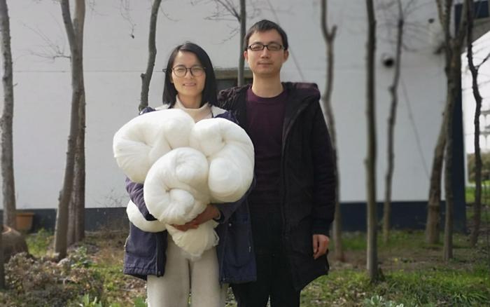 于建刚和妻子梅玉惠,手中是他们手工制作的蚕丝被。梅和鱼供图