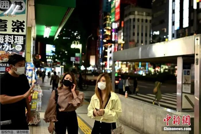 当地时间5月25日,东京新宿区,戴口罩的人们穿过街道。