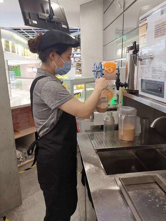 CoCo都可一家门店,店员在用吧勺搅拌奶茶