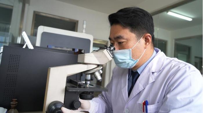 (张宇正在用显微镜分析样本斑迹)