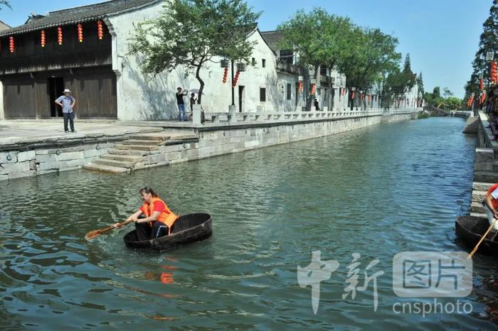 图为湖州古镇,一位民众正划着木桶船。中新社 张茵 摄