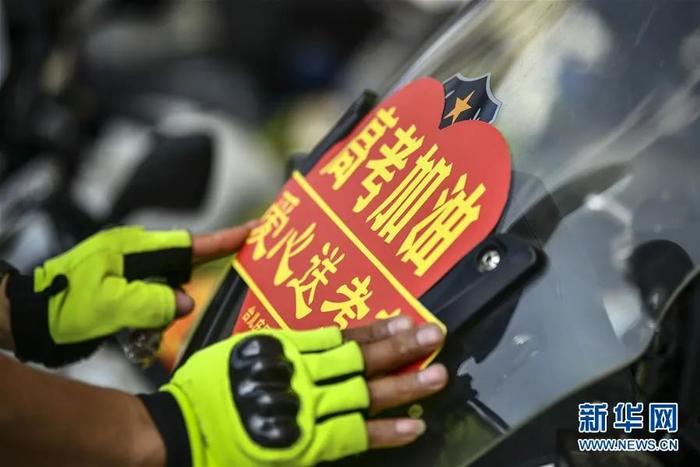 ▲7月6日,山东省枣庄市台儿庄公安分局交警大队民警在车辆上粘贴爱心送考标识。新华社发(高启民 摄)