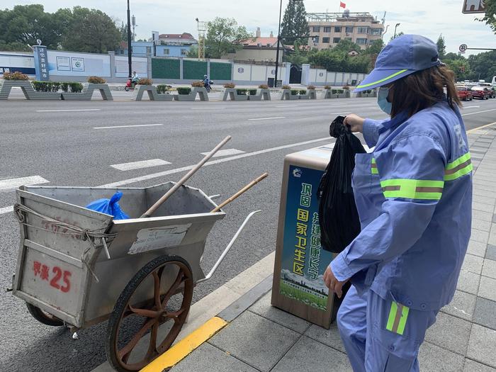 环卫工人张玉梅将路边垃圾桶内的垃圾全部清运到小推车里。 澎湃新闻记者 栾晓娜 摄