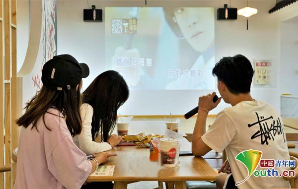 学生在食堂内边吃饭边唱歌。
