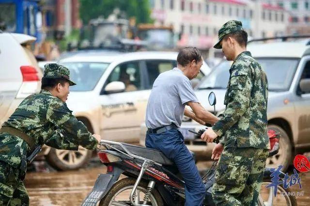 武警官兵帮助群众将车辆推出淤泥(图源:羊城晚报)