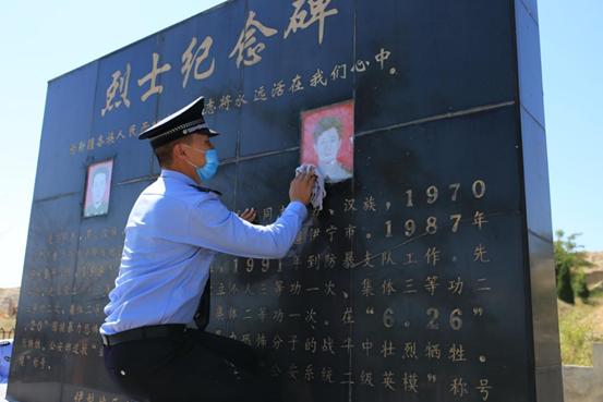 图:伊犁州公安局的干警在擦拭龙飞和孔永强烈士的纪念碑