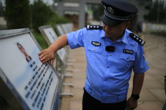图:和田烈士陵园,木拉提在擦拭牺牲战友简介牌上的雨水