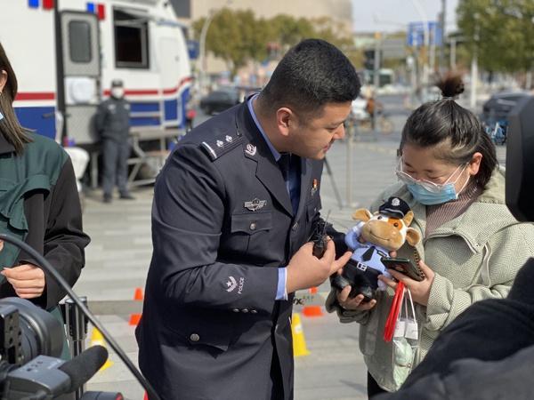 虹桥龙柏派出所民警汤岸鑫（左）向一位获奖市民送出警察牛牛卡通玩偶。