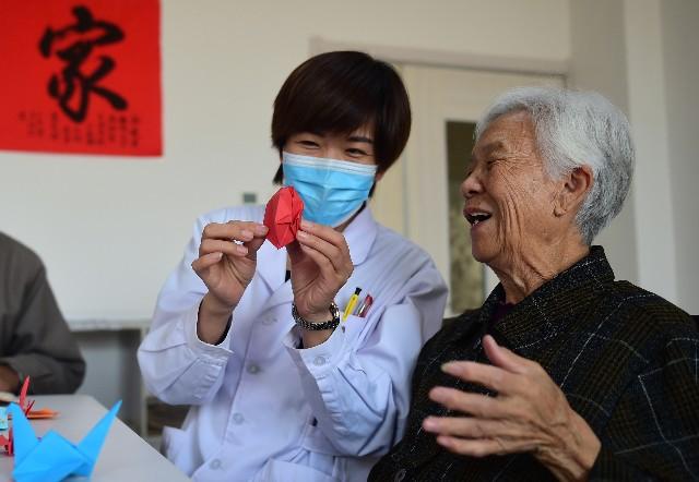 11月6日,省级医养结合试点单位沧州青县康泰养老护理中心护理人员与老年人一起折纸。新华社。