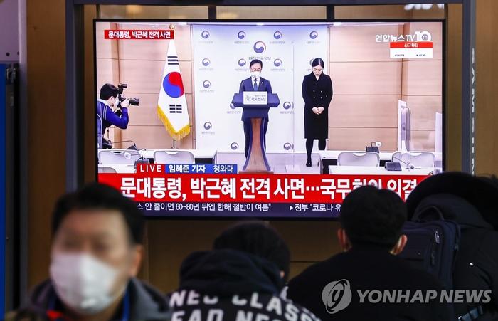 今天(24日)上午,韩国民众在首尔站观看韩国法务部长官宣布特赦的电视画面(图自韩联社)