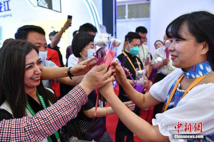 资料图:5月8日,海南省海口市,首届中国国际消费品博览会举行新疆日活动,推介新疆名优产品。图为来自新疆的工作人员在现场向参与活动的参观者派发棉花花束。 中新社记者 崔楠 摄