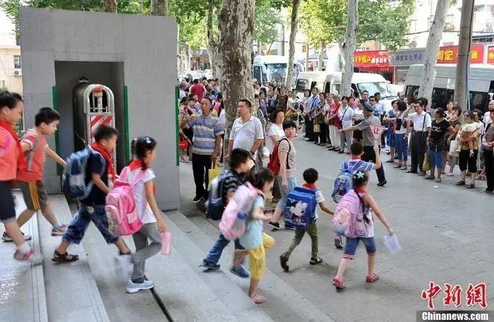 资料图:武汉一小学门外等待学生放学的家长们。中新社发 张畅 摄