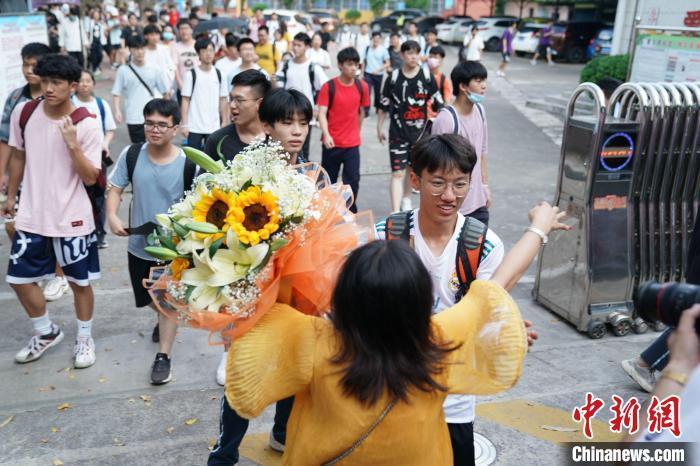 资料图:6月8日,广西南宁第二十九中学考点外,考生家长捧着花与考生拥抱。陈冠言 摄