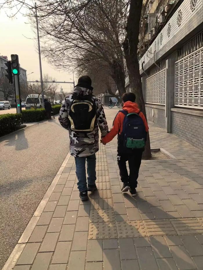 ▲放学后,尚维(左)牵着轩轩(右)的手,送他回家。 受访者供图