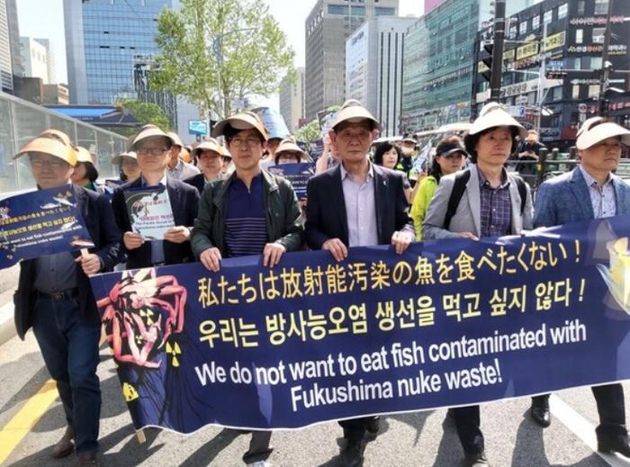 韩国市民团体手举“我们不想吃福岛核辐射鱼”的横幅在街头游行(社交媒体截图)
