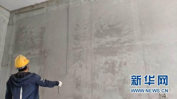 4月27日,一名工人在贵州医科大学新校区一期工程查看施工完成的磷石膏喷筑墙体。新华网 黄勇摄