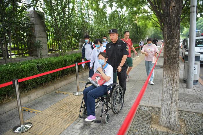 北京中考首日东直门中学考点：工作人员用轮椅送崴脚考生进考场