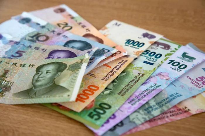 ▲这是民币4月27日在阿根廷布宜诺斯艾利斯拍摄的国民币和阿根廷比索纸币。（新华社发）