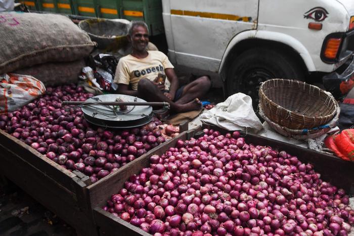▲印度加尔各答，一名商贩在市场上出售洋葱。图/新华社