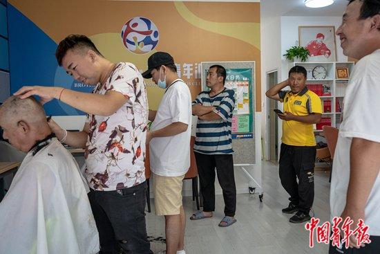 9月5日下午,北京市朝阳区费家村,付丛荣(右二)在“小哥加油站”排队等待理发。