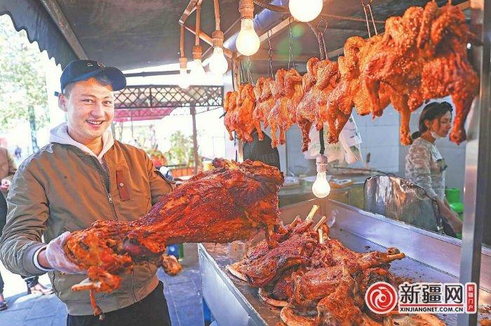 10 月 13 日,在天山区领馆巷,网红打卡点“和田美丽家乡烤全羊”的工作人员展示烤全羊。 (全媒体记者米热扎提·木塔力甫摄)