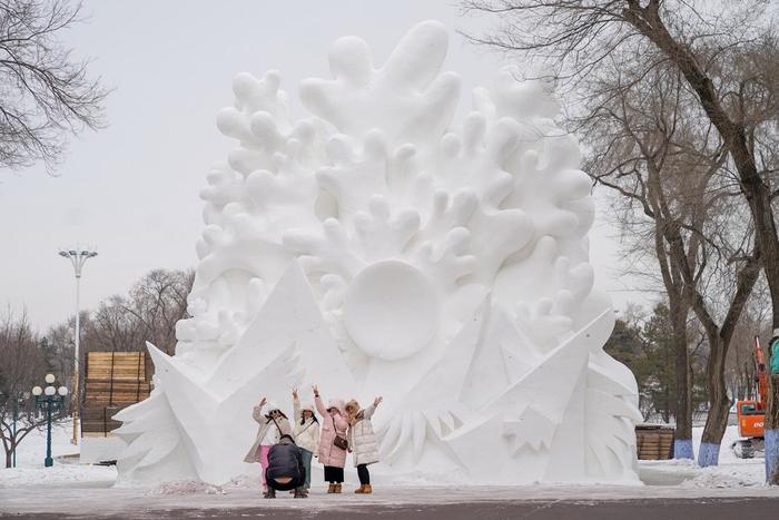 2023年12月4日，黑龙江哈尔滨，游客在雕刻成型的雪雕前拍照打卡。