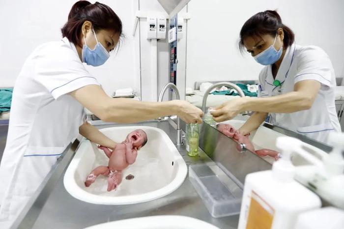 当地时间2023年7月11日,越南河内,一名护士在医院为一名新生儿洗澡。IC photo 资料图