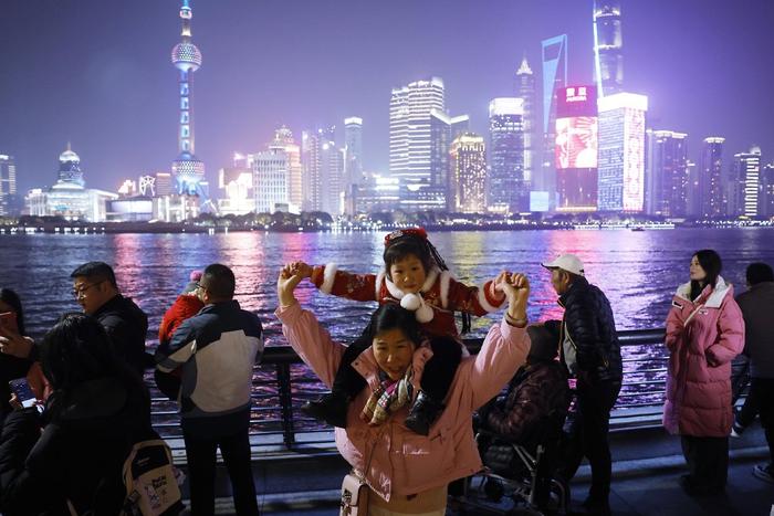 2024年2月9日，上海，搭客带着孩子在外滩滨江步道上赏识黄浦江两岸美景。中新社记者 殷立勤 图