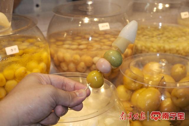 在邕州古城·三街两巷的一家酸嘢店,店家将酸嘢穿成串给顾客品尝 本报记者 冯源/摄