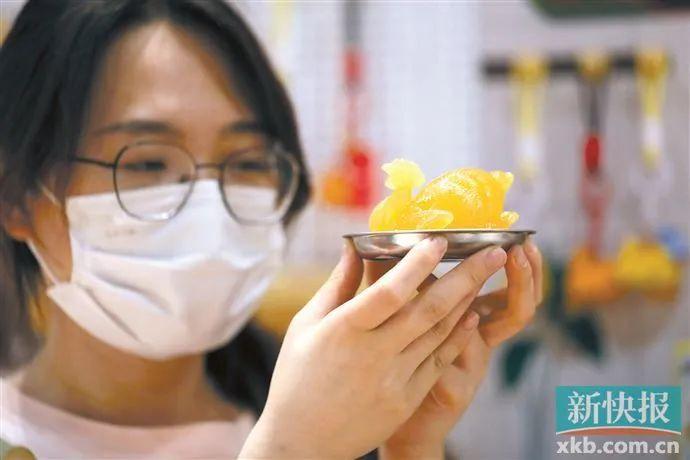 ▲5月23日,粤博的工作人员在展示玉雕鸡摆件以及配套的不锈钢碟子。该文创主体由树脂制作。