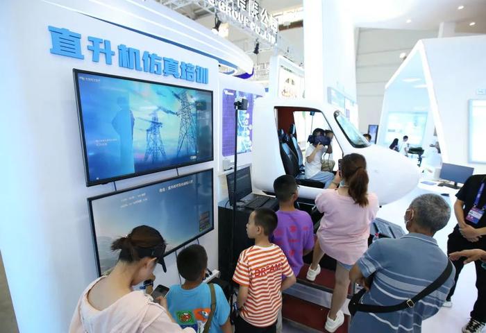 2023年8月20日,云南昆明,第七届中国-南亚博览会资源经济馆内,小朋友们排队体验仿真直升机
