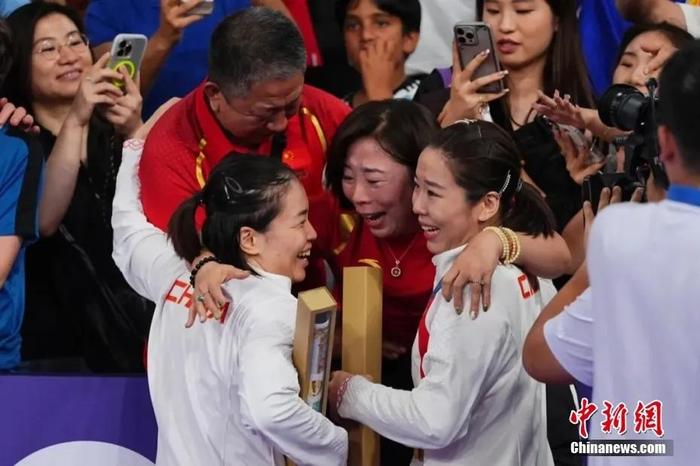 当地时间8月3日,在巴黎奥运会羽毛球女子双打比赛中,中国组合陈清晨/贾一凡2比0胜中国组合刘圣书/谭宁,获得金牌。图为陈清晨、贾一凡(右)与贾一凡父母拥抱。中新社记者 赵文宇 摄