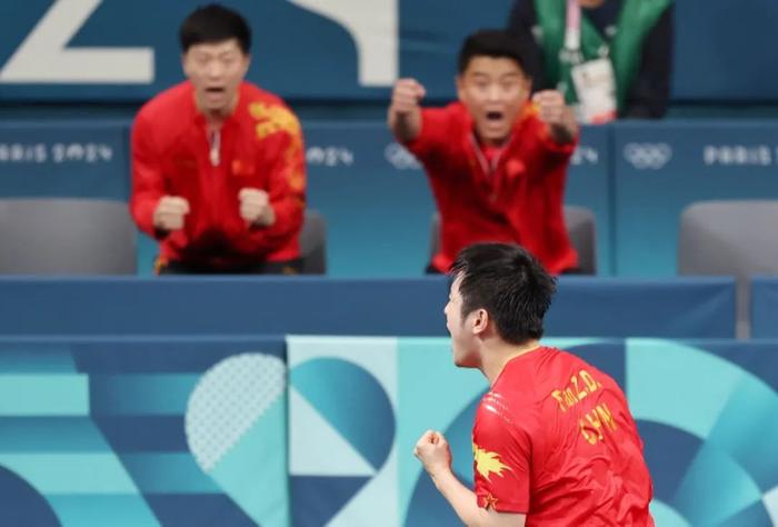 图为樊振东(右下)、马龙(左上)和教练王皓(右上)在比赛中庆祝得分。