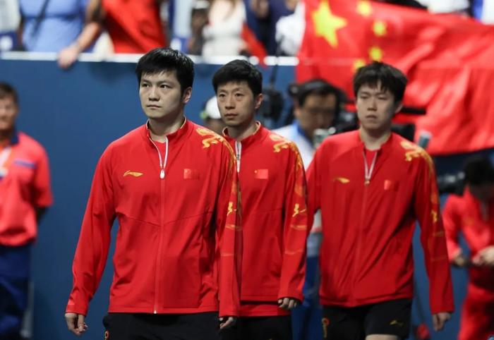 图为比赛即将开始,国乒男团选手樊振东、马龙、王楚钦(自左往右)步入赛场。