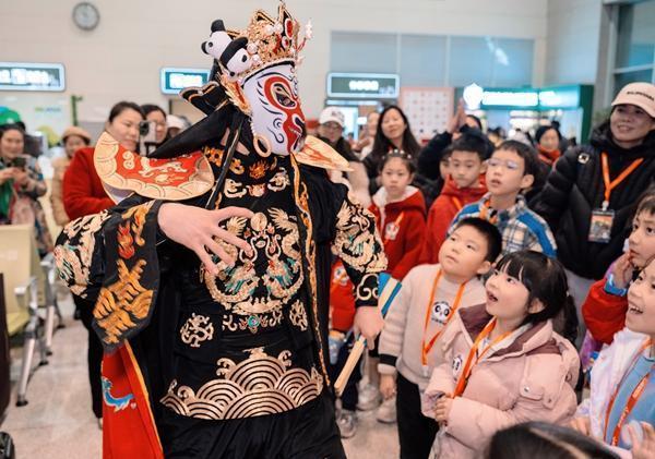 1月30日,Y987次“非遗主题”熊猫专列出发前,变脸演员正在与小游客互动。孟宽/摄