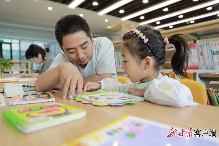 在金塔县图书馆内,家长带着孩子享受温馨的阅读时光。