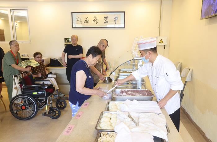 大兴区亦庄镇区域养老服务中心，老年人在排队打饭。新京报记者 王贵彬 摄