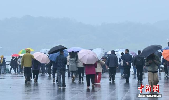 3月24日，游人撑伞前往西湖游览。中新社记者 王刚 摄