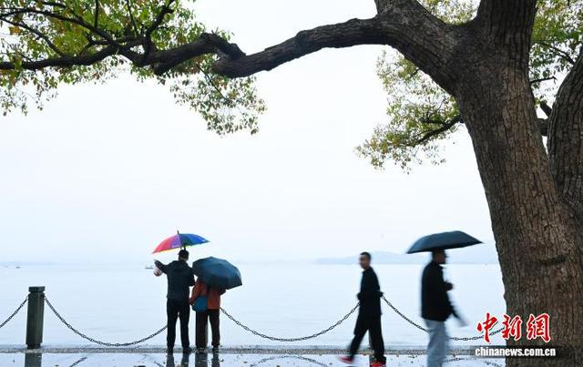 3月24日，游人在阴雨天气撑伞游西湖。中新社记者 王刚 摄