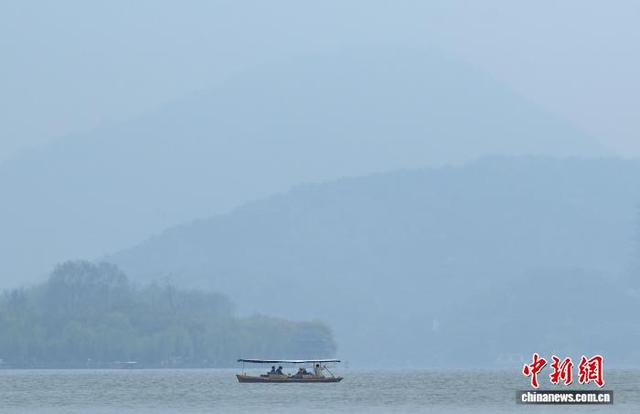 3月24日，游人泛舟欣赏西湖山水。中新社记者 王刚 摄