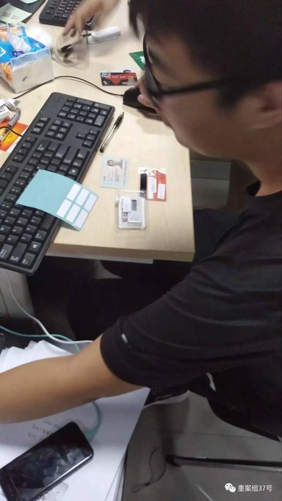 一名工作人员正在检验“兼职人员”的身份证、银行卡、U盾。视频截图
