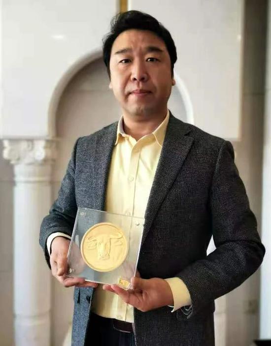 2021年中国人民银行发行的辛丑(牛)年金制纪念币作者刘中先生手捧2公斤金制纪念币合影留念