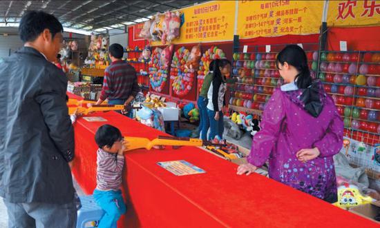 2017年1月2日,广西,公园射击游戏摊前的游客和玩家。