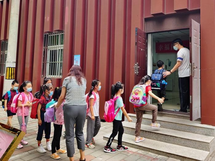 北京十八中附属实验小学新生在老师的引导下走进校门。