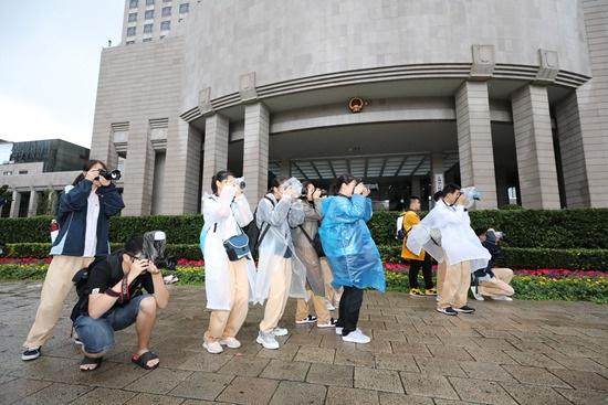 2019年10月2日,上海一所中学的摄影社成员在上海市政府门口冒雨拍摄升旗仪式。陈淑珉/摄
