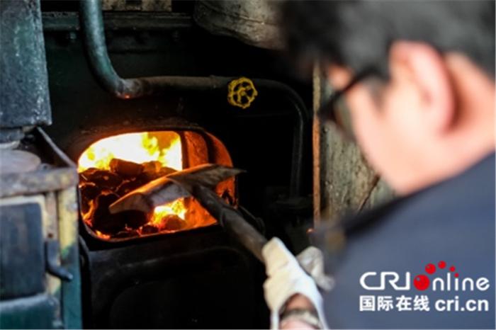 列车员正在往各个车厢连接处的锅炉中加煤。摄影:沈湜