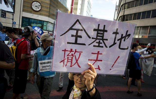 图为日本人高举美国撤军的标牌