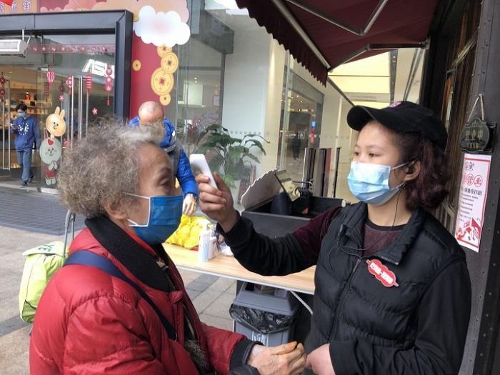 (店员为顾客测量体温)